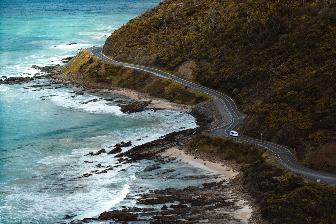 Luxury sedan driving on a coastal road at golden hour